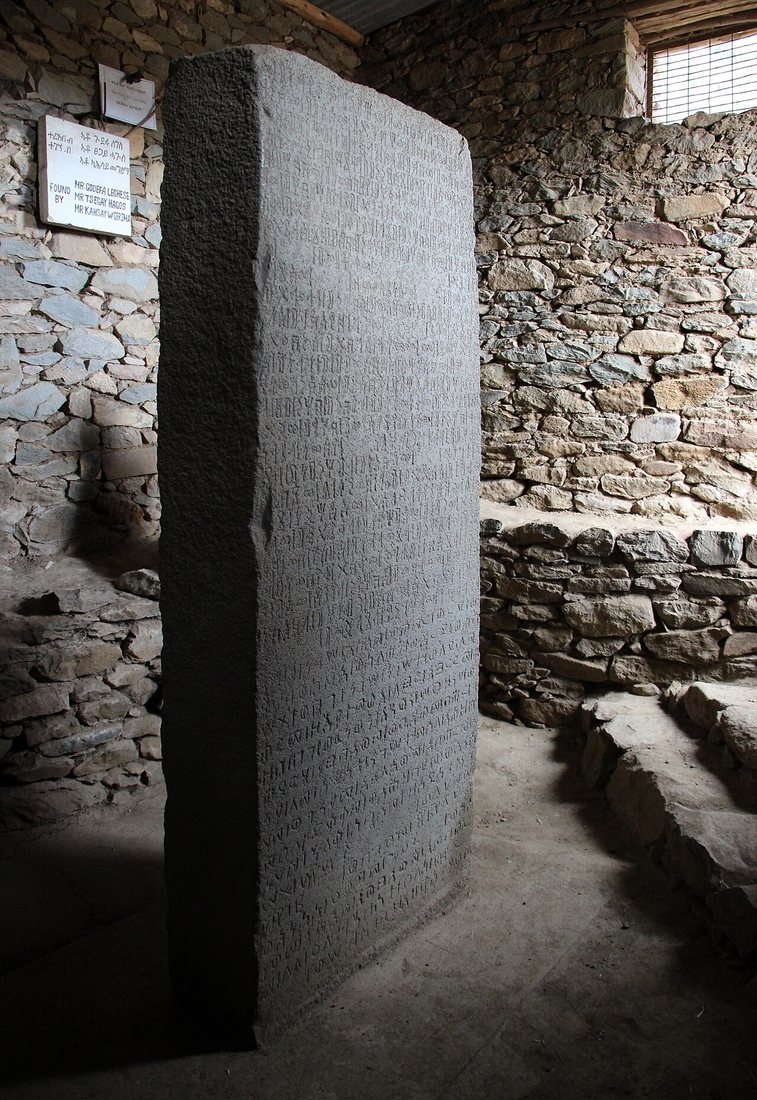 The Ezana Stone at Aksum, now housed in a small shelter. This face carries the same text in Geʽez written twice, in South Arabian and in Ethiopic script; the Greek version is on the opposite face.