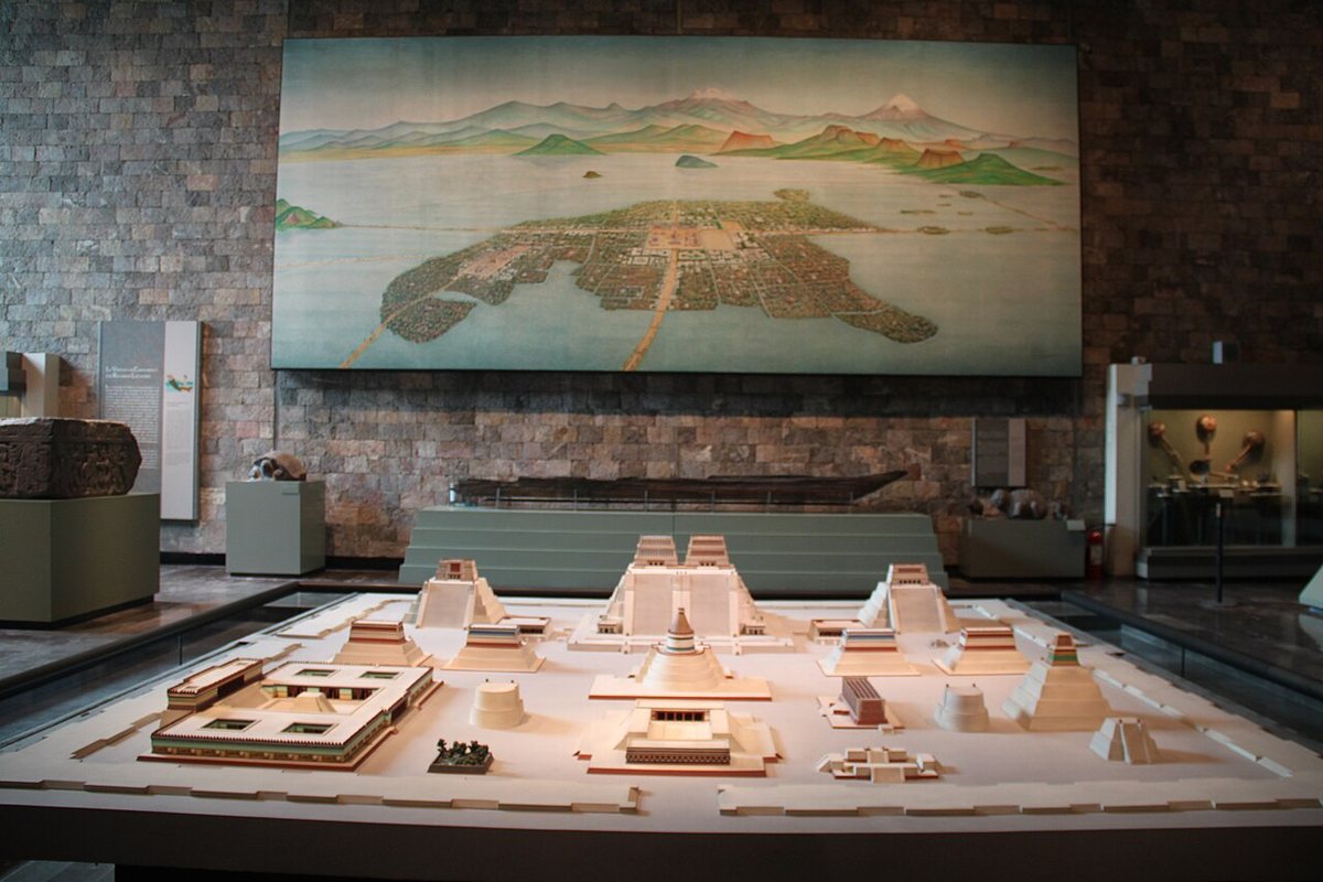 A model of the ceremonial precinct of Tenochtitlan in the National Museum of Anthropology, Mexico City, with the twin temple of the Templo Mayor at the back in the centre. The painting on the wall shows the island city in Lake Texcoco, joined to the shore by causeways.