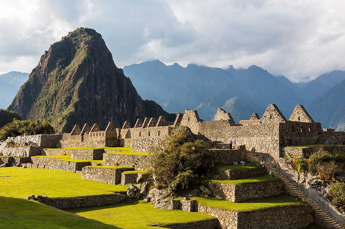 Machu Picchu, a 15th-century Inca site on a mountain ridge about 2,430 metres above sea level over the Urubamba valley, abandoned about a century later. Terraces and stone houses in the foreground, the peak of Huayna Picchu behind.