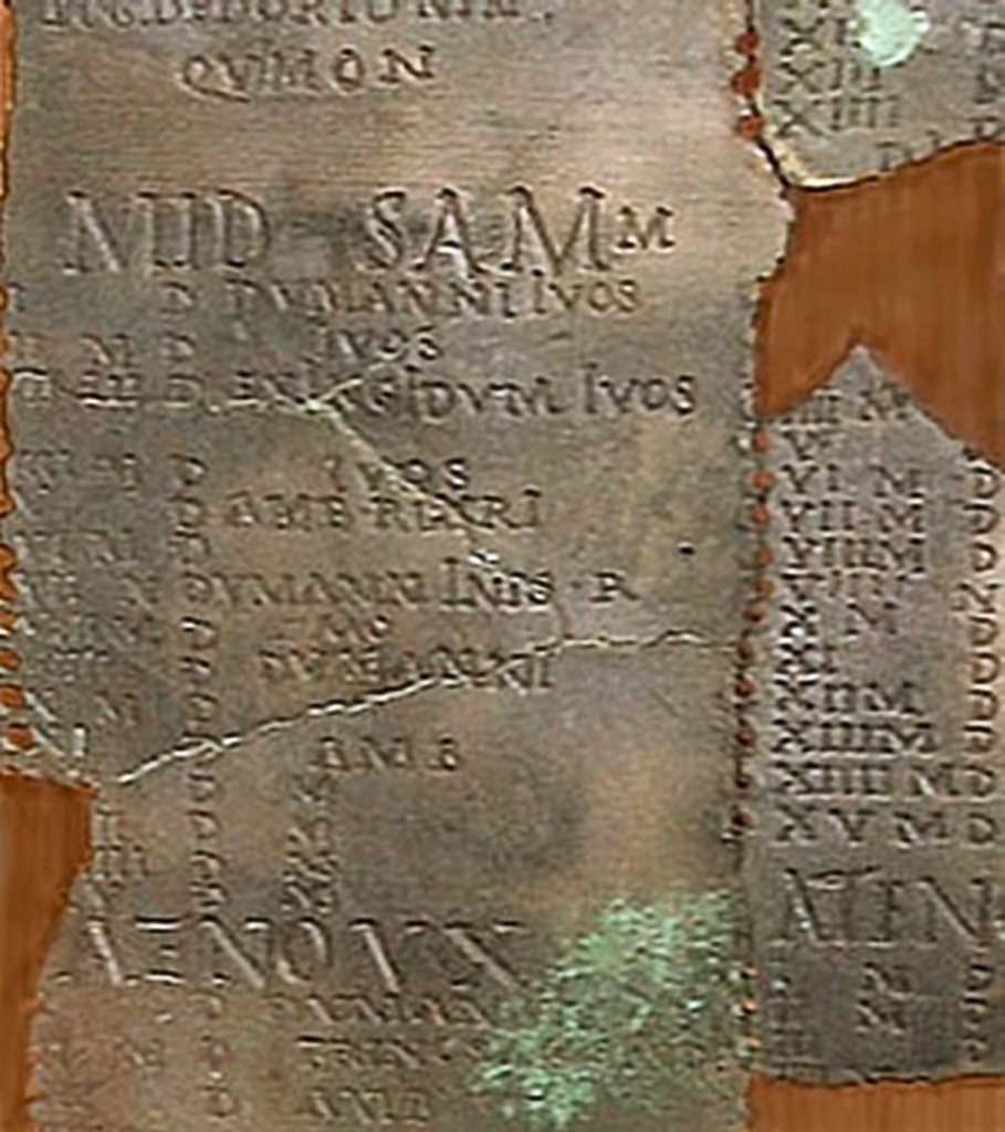 Detail of the Coligny calendar: the heading of the month Samonios (MID SAMON…), below it days with Roman numerals and notes such as DVMANNI IVOS, and at the bottom the word ATENOVX, which divides the month into two halves. On the right, a row of peg holes.