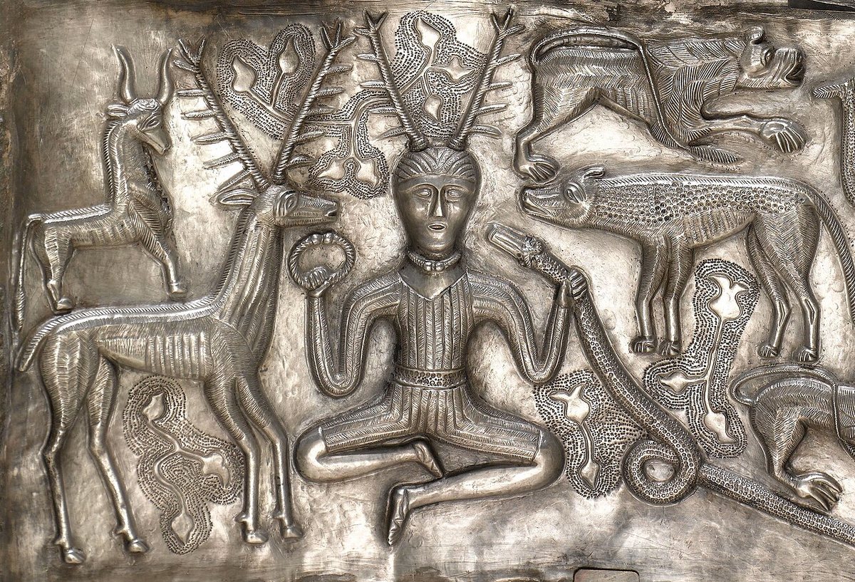 An inner plate of the Gundestrup cauldron: a seated antlered figure holds a torc in his right hand and a horned serpent in his left, surrounded by animals. He is often identified with the Gaulish god Cernunnos, whose name is attested only on the Pillar of the Boatmen from Paris (1st c.); the identification is an interpretation, not a certainty.