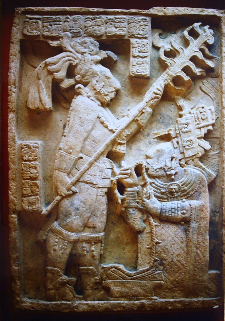 Lintel 24 from Yaxchilan (c. 723–726): Lady Kʼabal Xook performing a bloodletting rite, with King Itzamnaaj Bahlam III (Shield Jaguar) holding a torch above her. The glyphs along the top and at the sides give the date and names. British Museum.