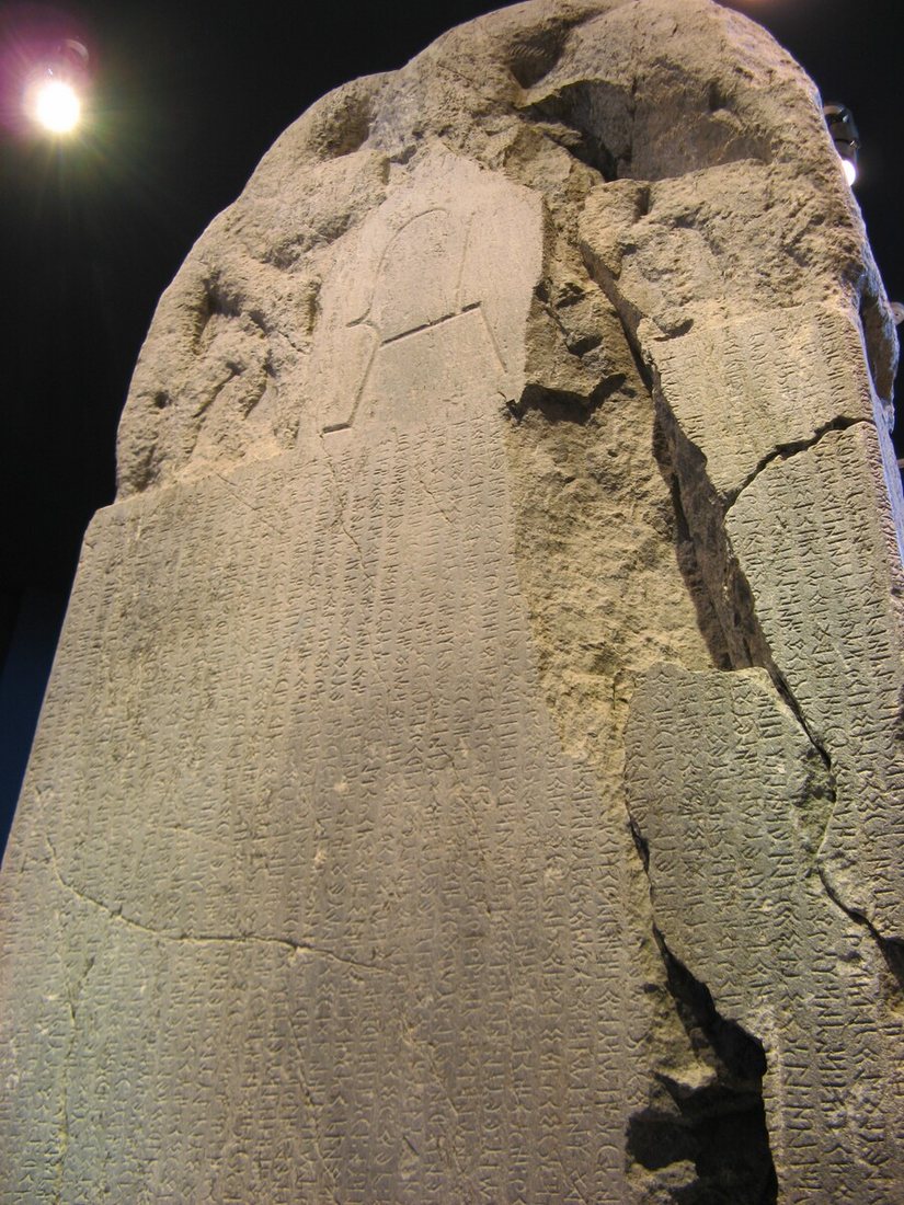 The upper part of the Kül Tigin stele, with vertical lines of the runic inscription. The stone is cracked and broken away in places.