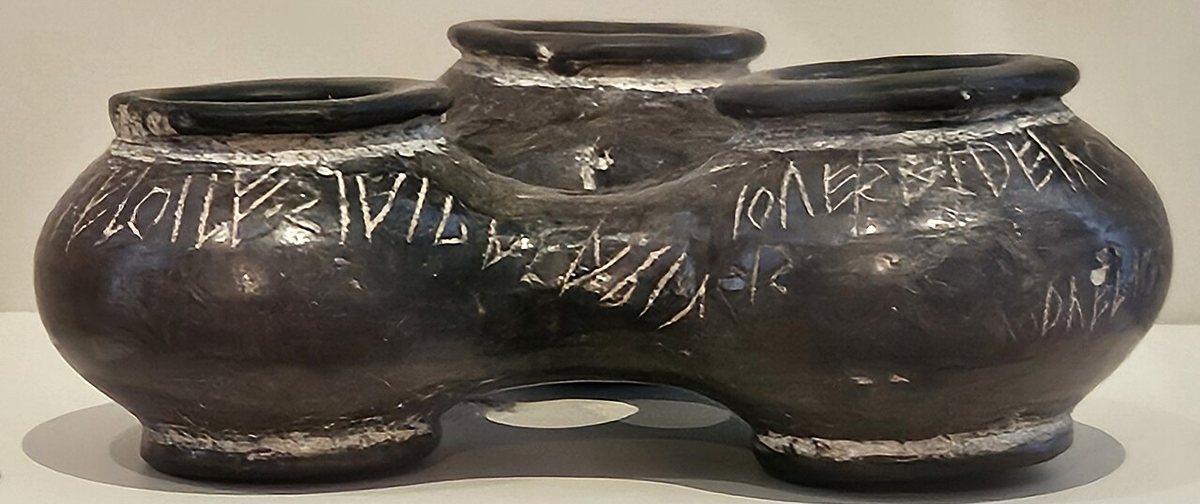 The triple vessel of black bucchero ware with the Duenos inscription, scratched from right to left without spaces between words. It was found in 1880 on the slope of the Quirinal in Rome and is dated anywhere from the 7th to the 5th century BCE. State Museums, Berlin.