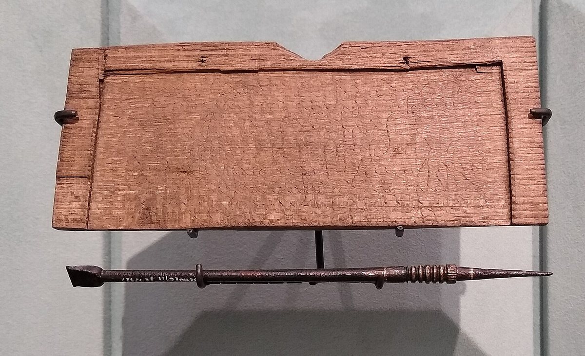 A wooden writing tablet and a metal stylus from London. The wax is gone, but the stylus cut through into the wood: the text, dated 8 January 57 CE, records a debt of 105 denarii for goods and is the oldest known record of a commercial transaction in the City of London. On display at the London Mithraeum.